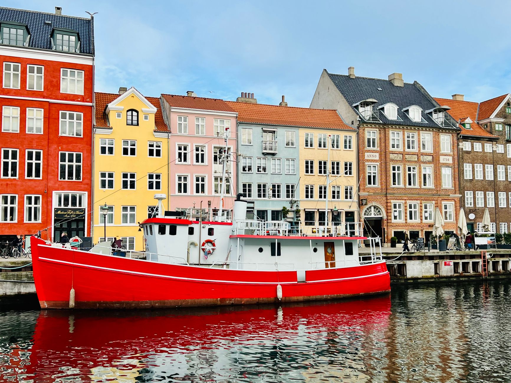 Farverige huse ved en havnekaj med en rød båd i forgrunden